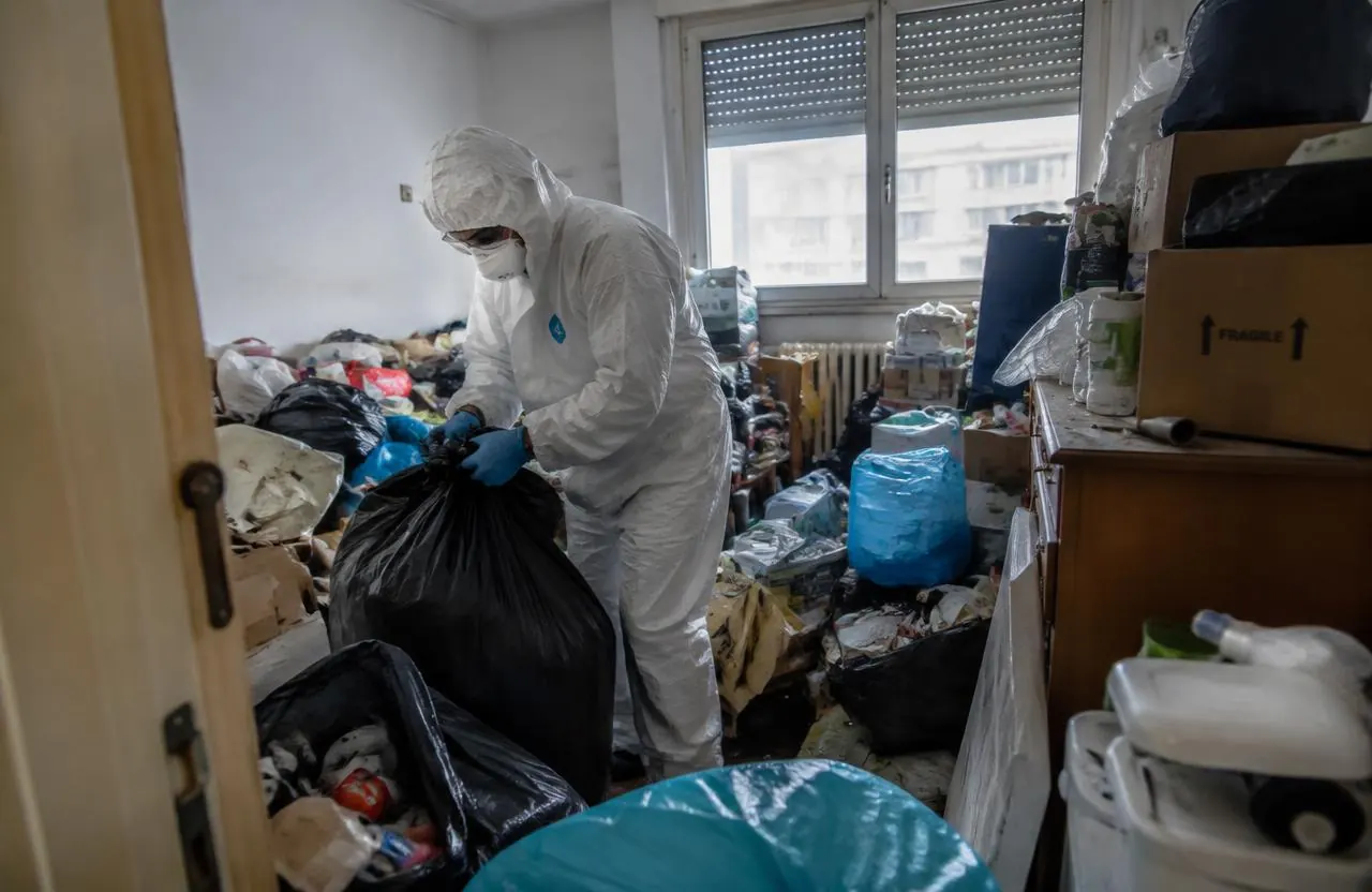 Mitarbeiter in Schutzanzug räumt eine stark vermüllte Wohnung